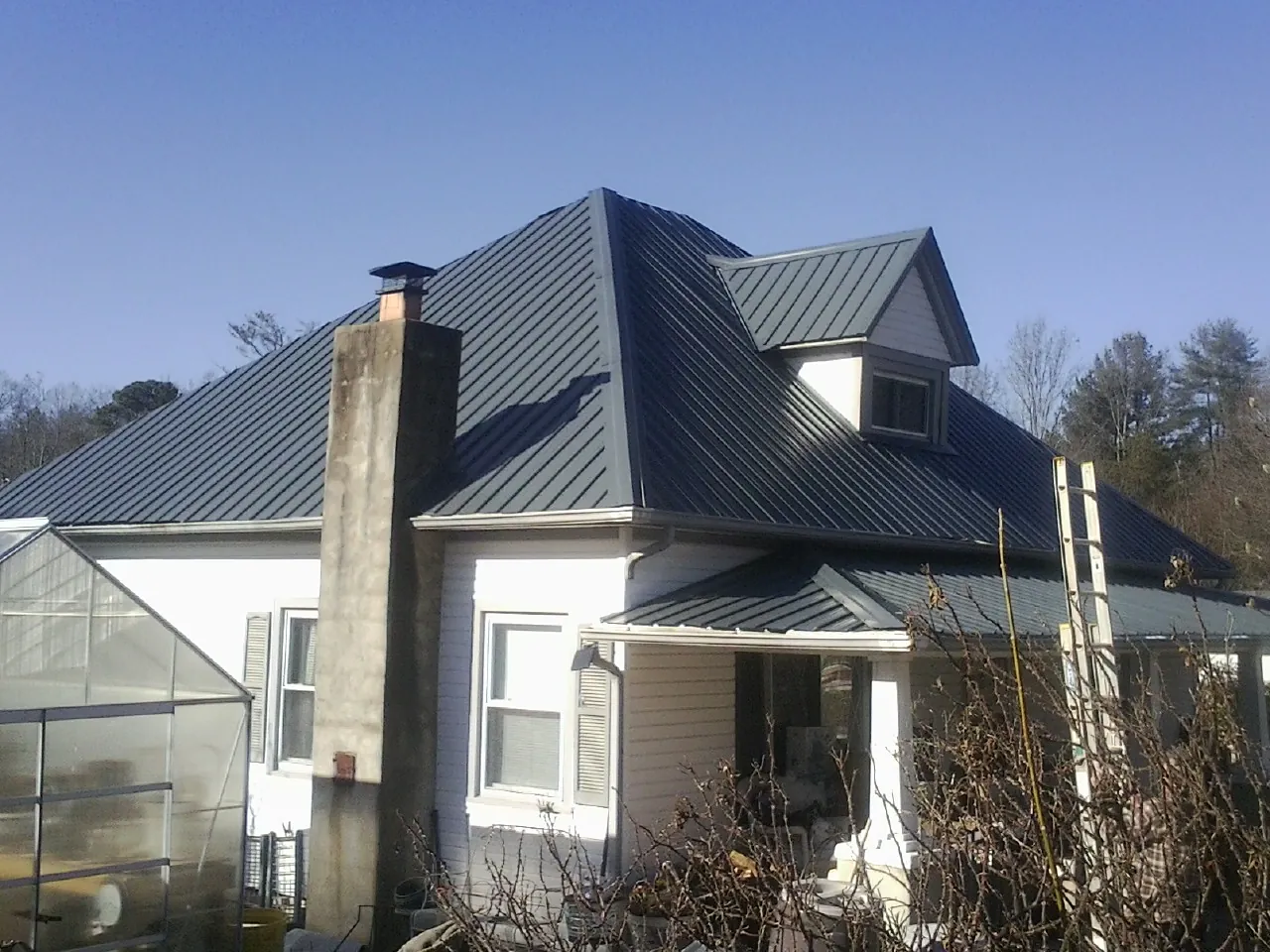 Dark blue standing seam metal roof on a white farmhouse with dormer — Slate & Tile Roof Repair by Roofing Brothers in Anvik