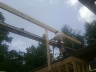 Carpenter setting a ridge beam over a new addition frame — Ice Dam Removal by Roofing Brothers in Anvik