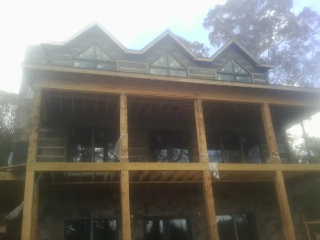 Dormers and porch framing on a large log home under construction — Roof Coating work by our crew in Anvik
