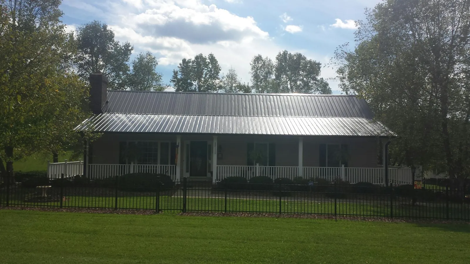 Gray metal roof on a brick ranch with a full width front porch — Gutter Guard Installation work by our crew in Anvik