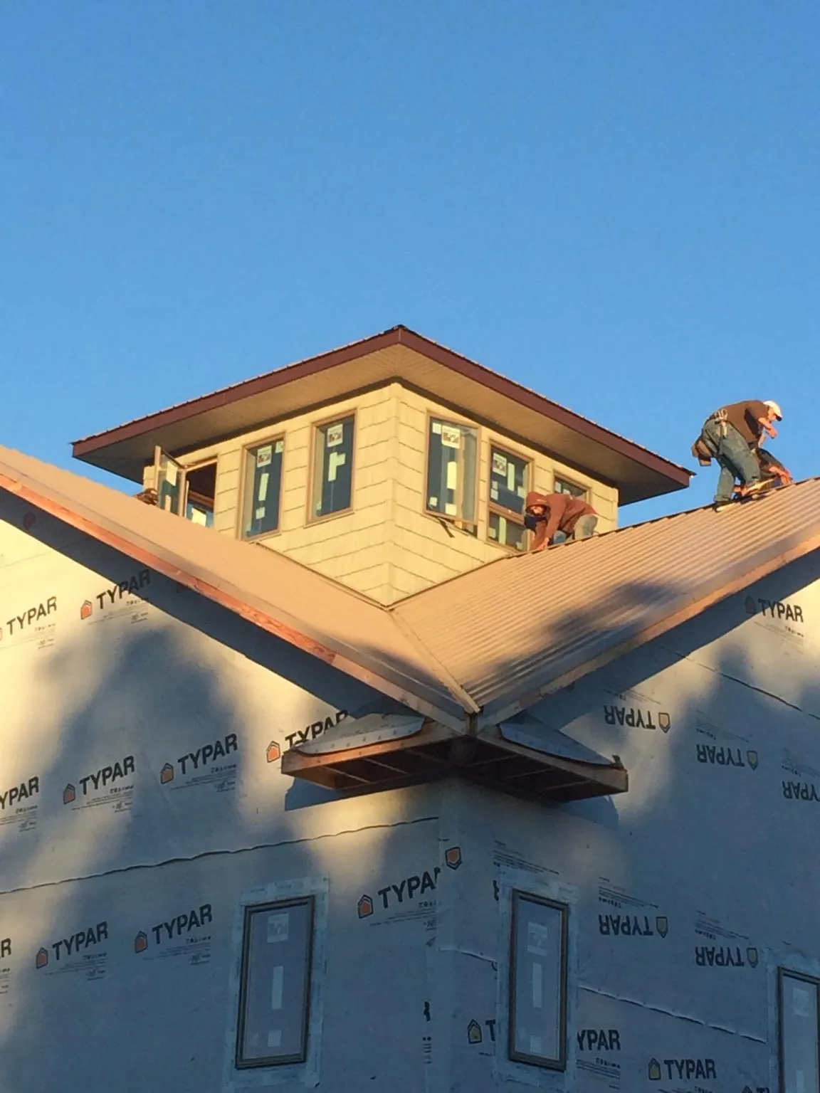 Roofers working around a rooftop cupola on a new metal roof at sunset — Roof Waterproofing in Anvik by Roofing Brothers